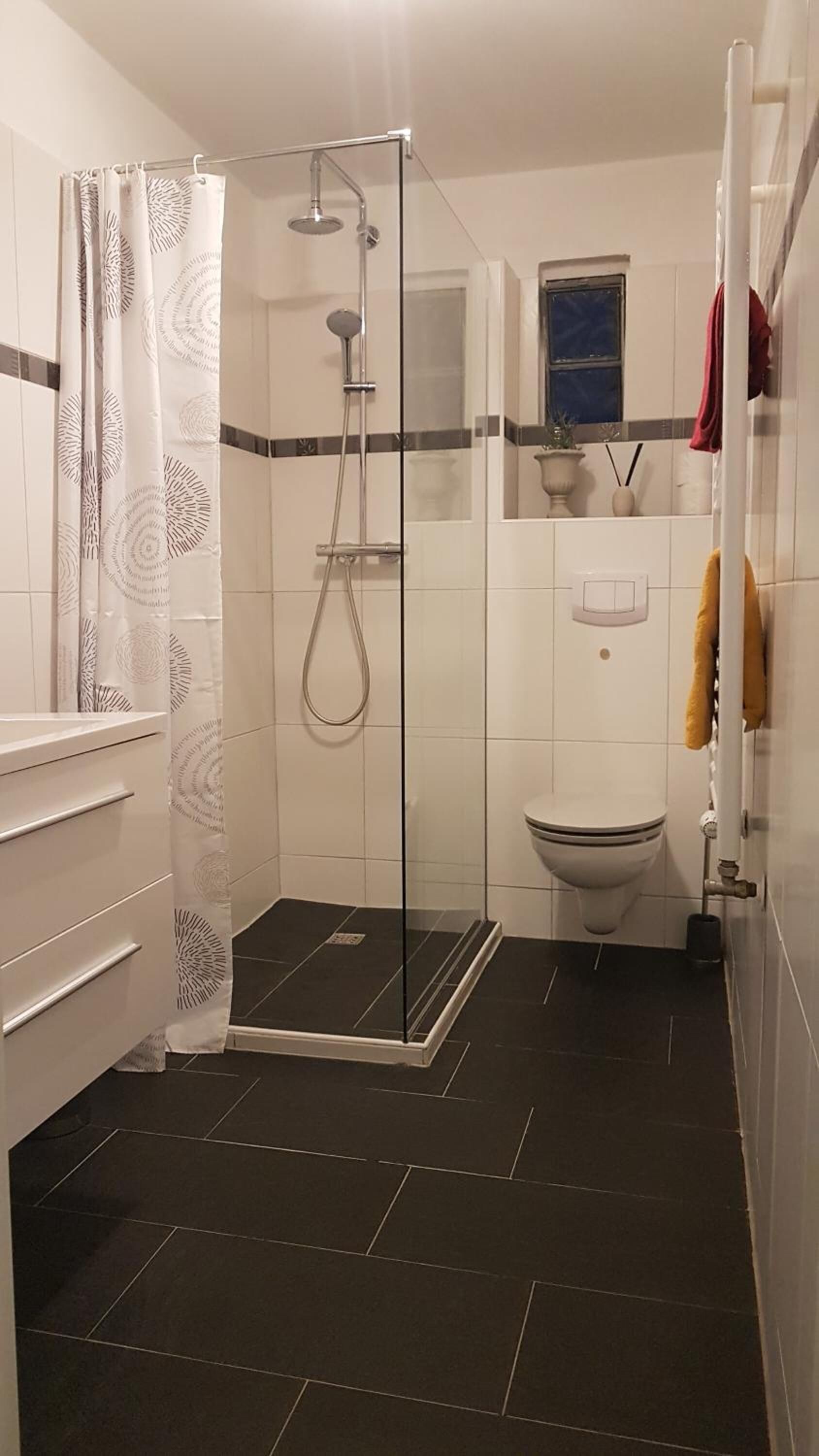 A bathroom with a glass-enclosed shower, a toilet, and a sink.