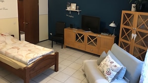 Una camera da letto con un letto, un divano, una TV su un mobile in legno e una porta.