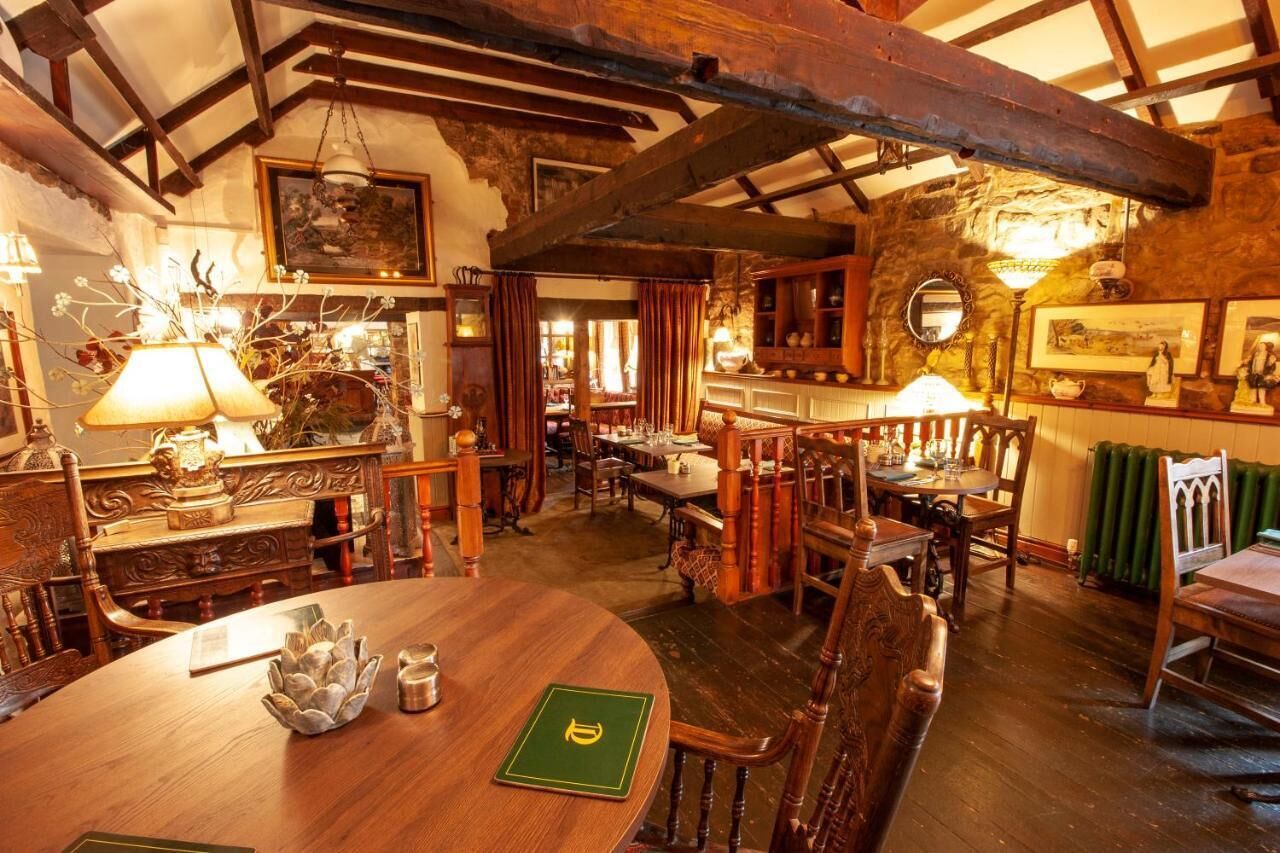 Comedor rústico con muebles de madera, techo alto con vigas a la vista y pared de piedra.