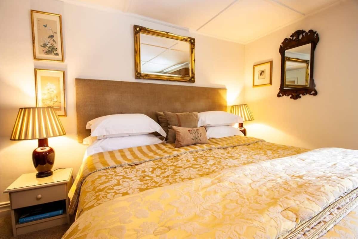 A hotel room with a large bed, two bedside tables, a headboard, and two wall-mounted mirrors.