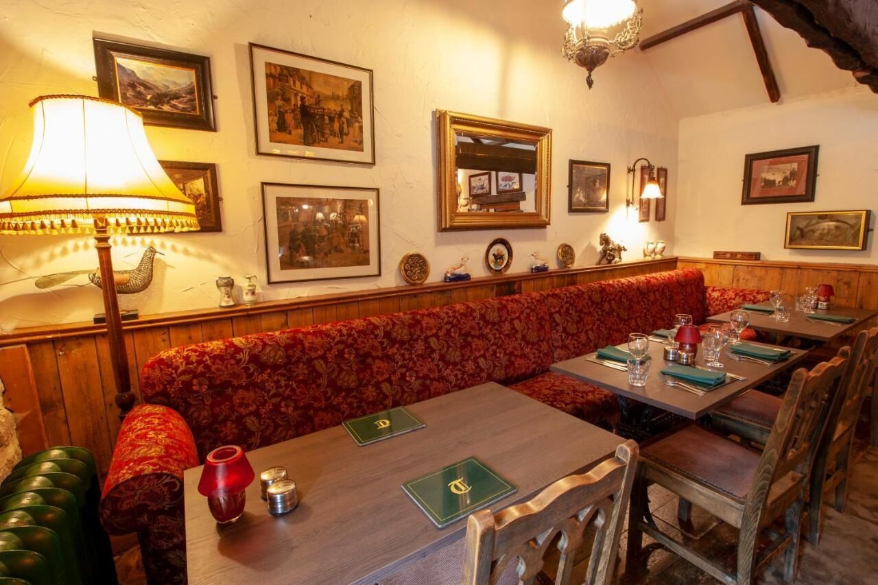 A restaurant with wooden furniture, a red upholstered bench, and framed pictures on the wall.