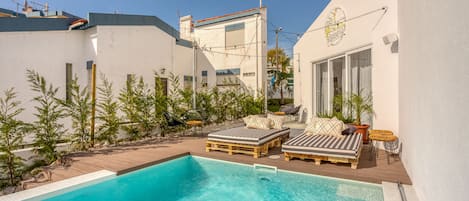 Una piscina al aire libre, sombrillas, sillones reclinables de piscina