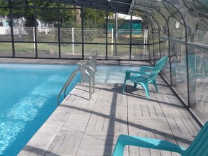 Una piscina al aire libre de temporada, sillones reclinables de piscina