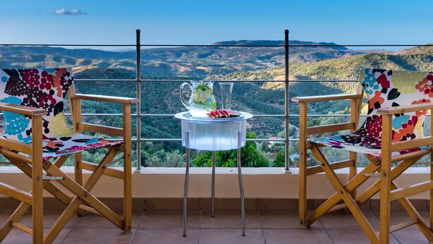 A balcony with two wooden chairs and a small table, overlooking a scenic landscape. - Villa Armonia Boutique Living (Chania)