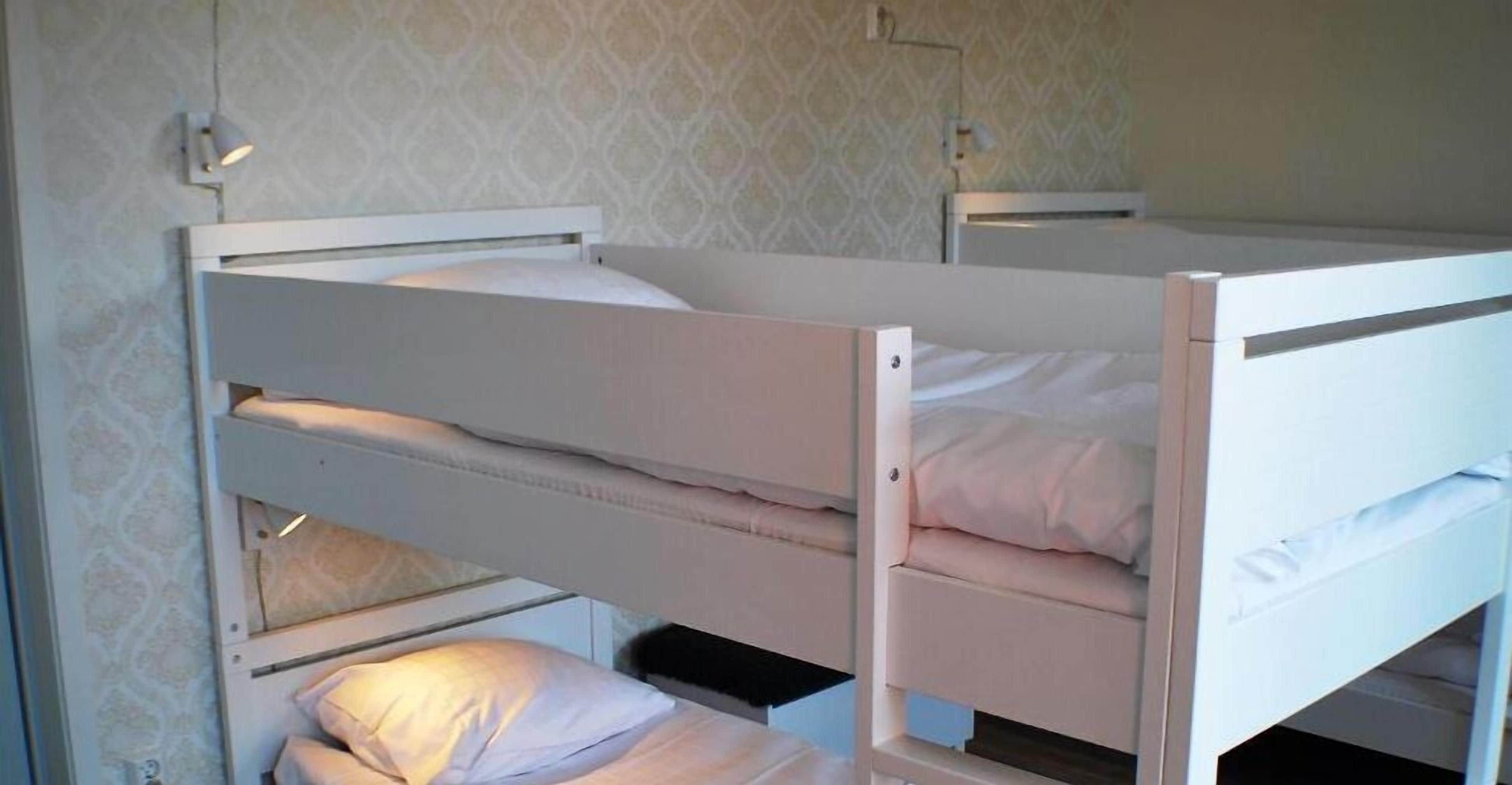 Habitación con literas, papel tapiz estampado y una mesita de noche pequeña con lámpara.