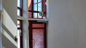 A hallway with a chandelier, a red door, and a window with a sign. - Go To Sleep Arvika - Hostel (Arvika)