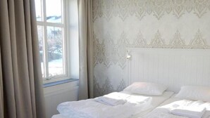 A hotel room with a bed, curtains, and patterned wallpaper. - Go To Sleep Arvika - Hostel (Arvika)