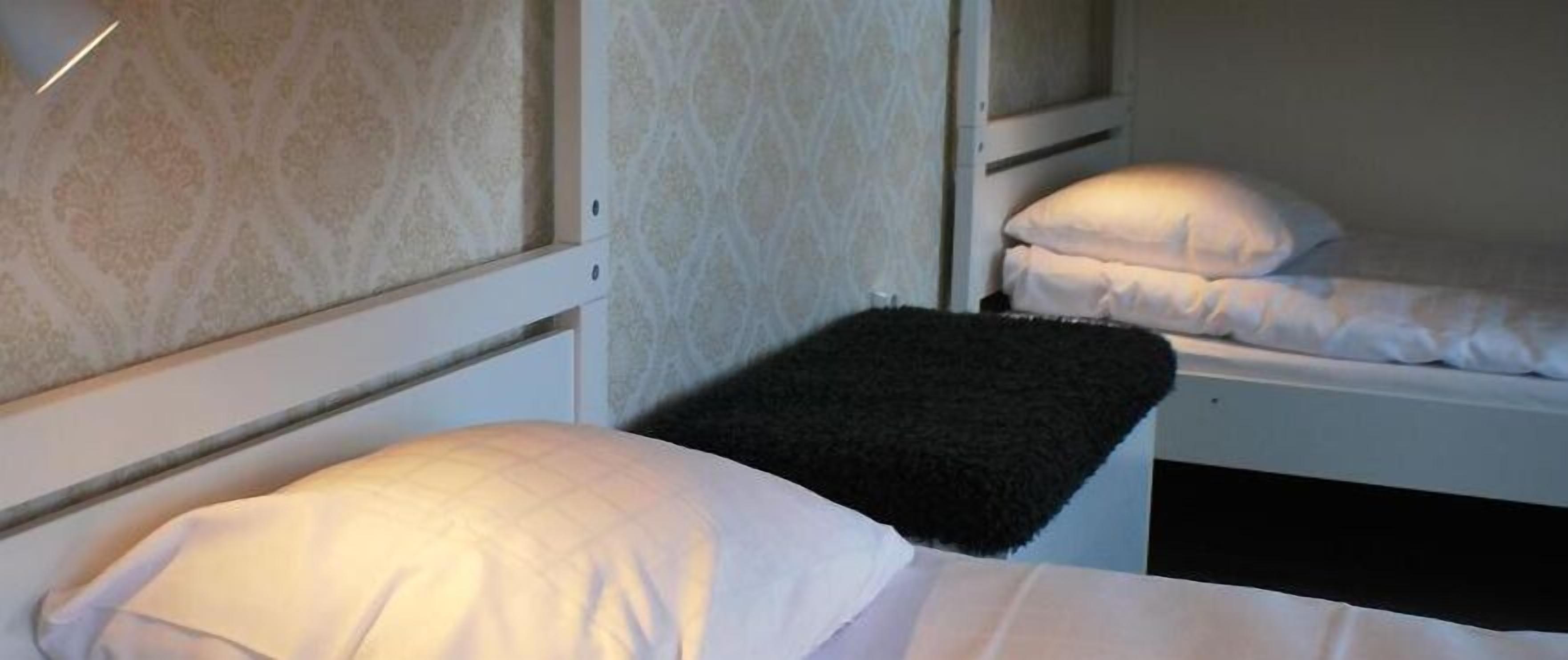 A hotel room with two beds, each with white bedding and pillows.