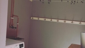 A compact laundry room with a Bosch washing machine, a drying rack, and a small table with a chair. - Go To Sleep Arvika - Hostel (Arvika)