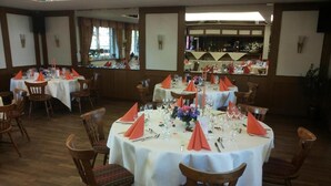 A dining area with round tables set for multiple guests, each table adorned with white tablecloths and orange napkins. - Hotel Gasthaus Schubert (Garbsen)