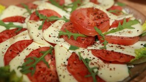 A wooden table with a salad consisting of tomatoes, cheese, and greens. - Hotel Gasthaus Schubert (Garbsen)