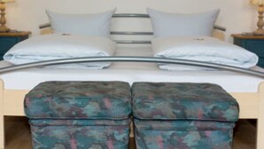 A double bed with a metal frame, two pillows, and matching ottomans. - Hotel Gasthaus Schubert (Garbsen)