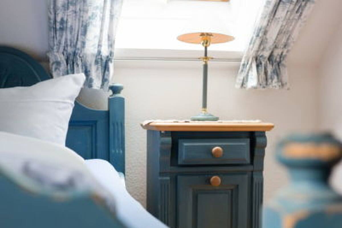 A bedroom with a bed, a nightstand, and a lamp.