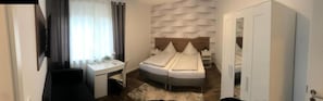 A bedroom with a bed, bedside tables, a desk, and a wardrobe.