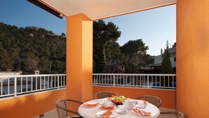 A round table with chairs on an outdoor balcony, set with plates, cutlery, and a fruit bowl. - Apt. Grande Ciruelo, A/C, community pool, Wifi, near beach 400 m (Cala Sant Vicenç)