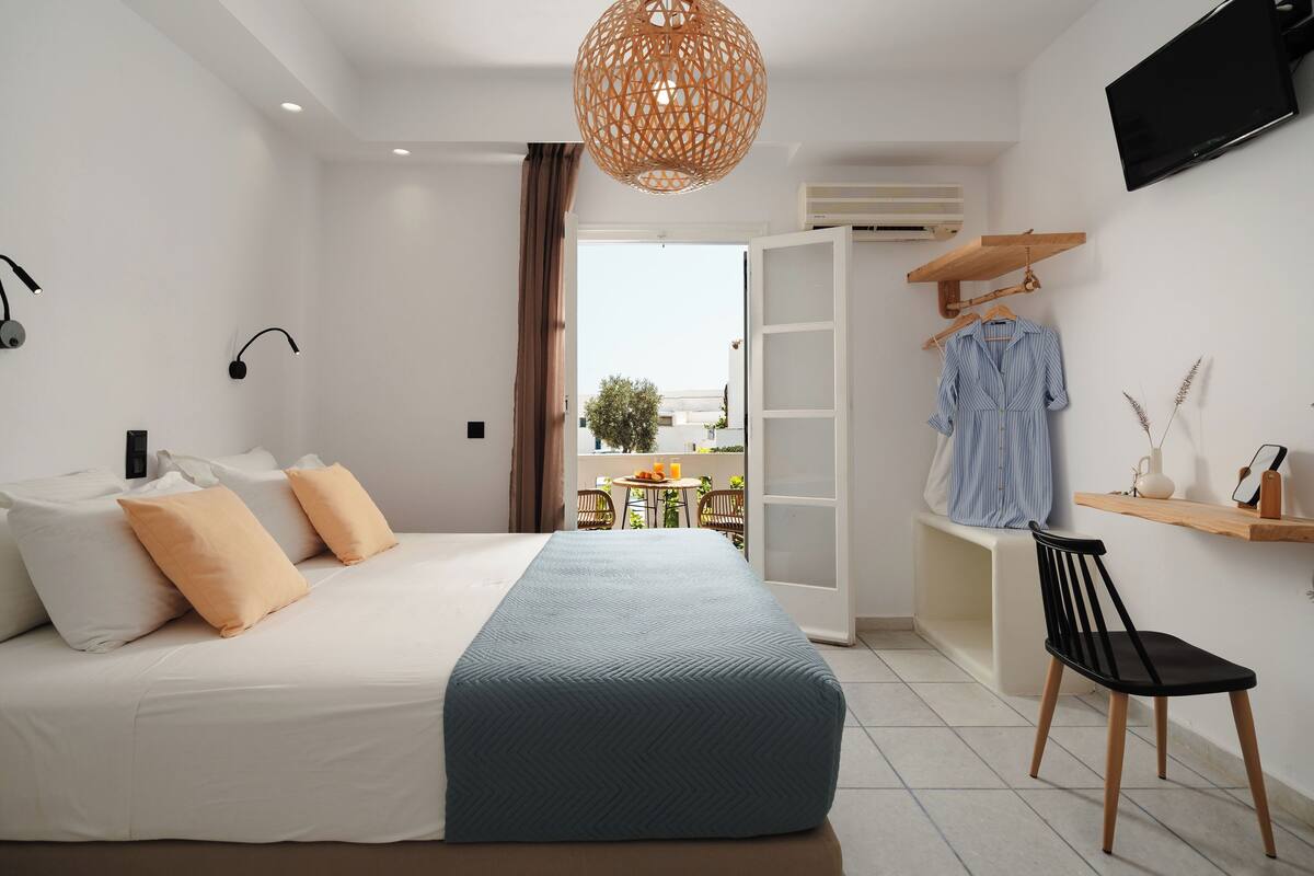 A bedroom with a bed, a chair, a TV, and a window.