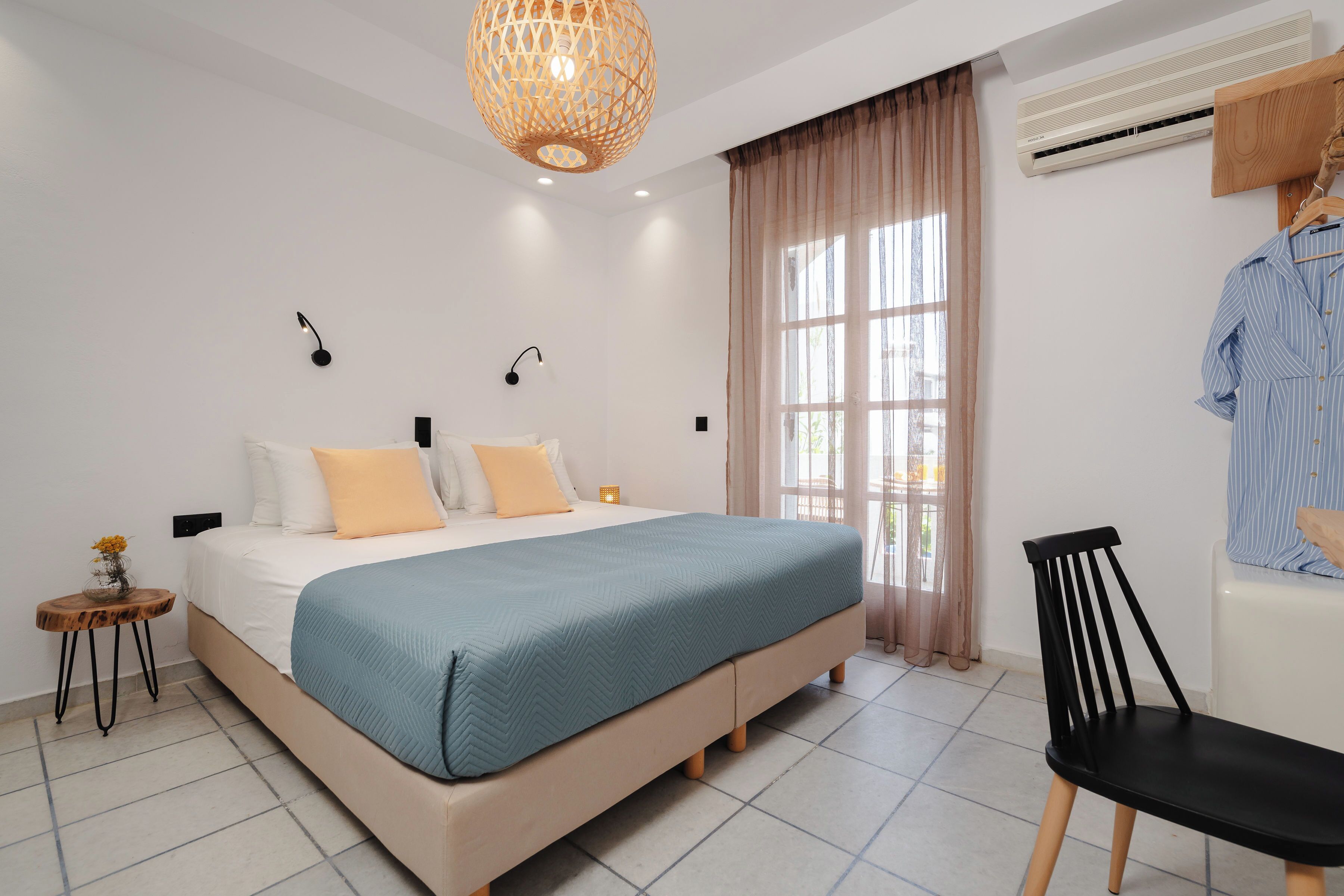 A bedroom with a bed, bedside tables, a hanging chair, and a window with curtains.