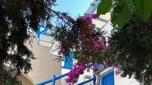 A traditional white building with blue accents, a stone staircase, and a balcony with flowers. - Sea View Apartments & Studios (Naxos)