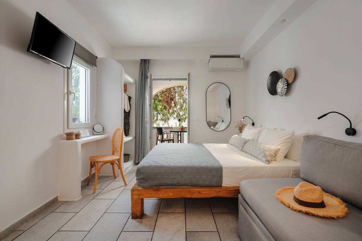 A modern bedroom with a bed, a sofa, a TV, and a desk.