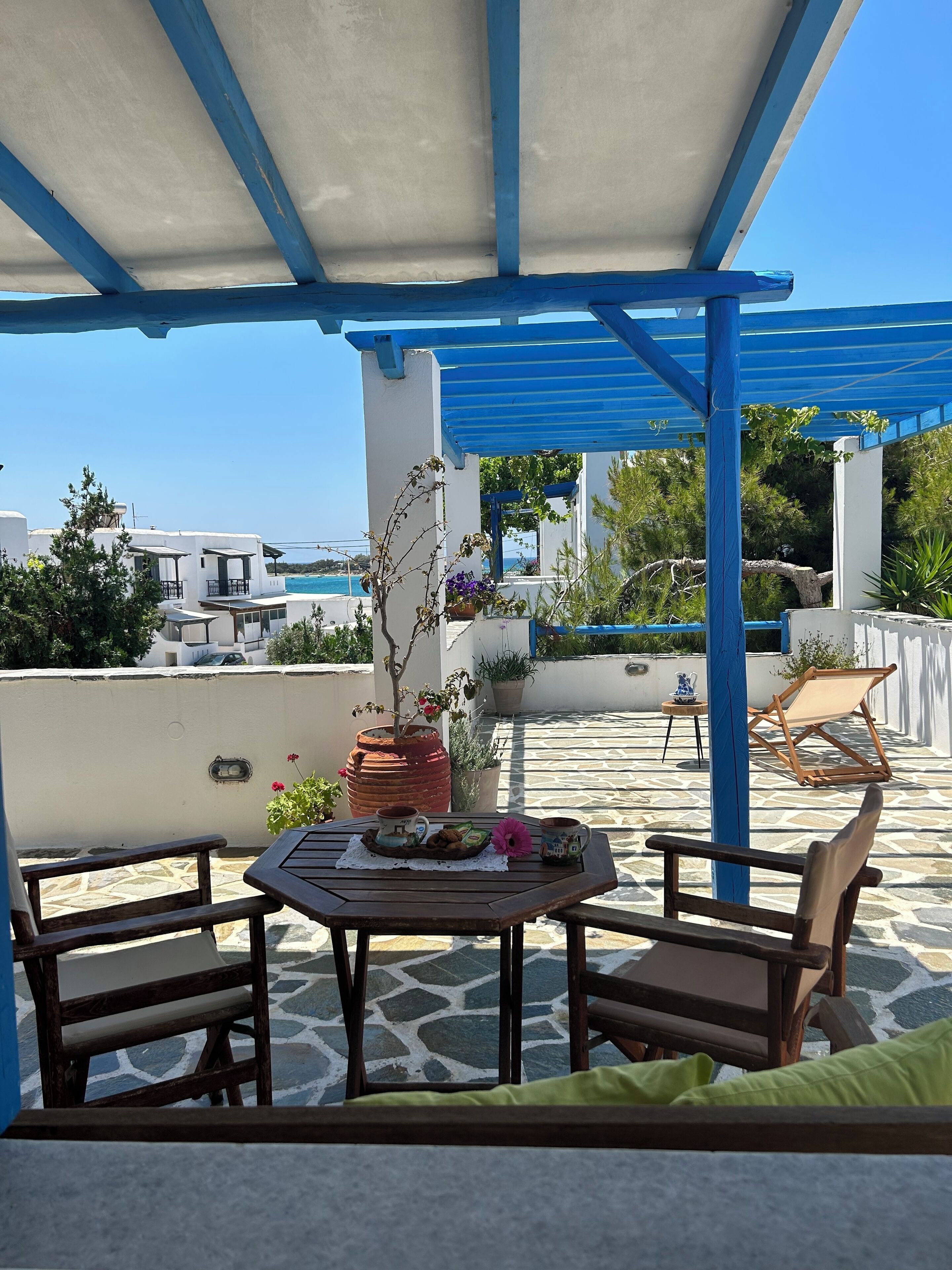Un espacio de estar techado al aire libre con una mesa preparada para dos, una silla y vista al mar.