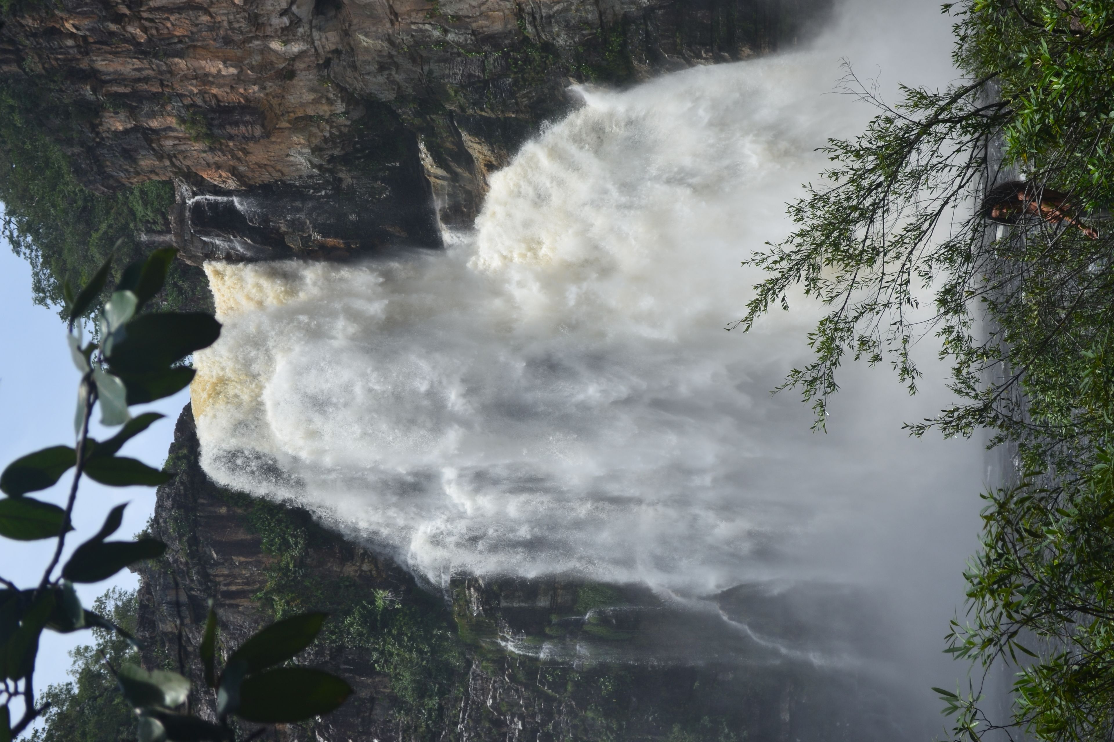 Ein Wasserfall stürzt über eine felsige Klippe, umgeben von viel Grün.