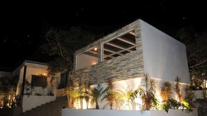 Una casa moderna con fachada de piedra, amplias ventanas y una entrada luminosa.