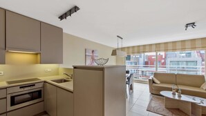 Una cucina moderna con elettrodomestici integrati, una zona pranzo con divano e tavolo, e ampie finestre che offrono vista sulla città.