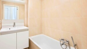 Un bagno con un lavandino bianco, uno specchio e una vasca da bagno con soffione.