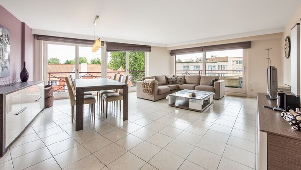 A spacious living area with a dining table, sofa, and a TV. - La Bohème 204 (Koksijde)