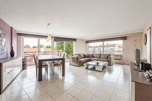 A spacious living area with a dining table, sofa, and a TV. - La Bohème 204 (Koksijde)