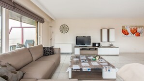 A modern living room with a sofa, coffee table, TV, and artwork. - La Bohème 204 (Koksijde)