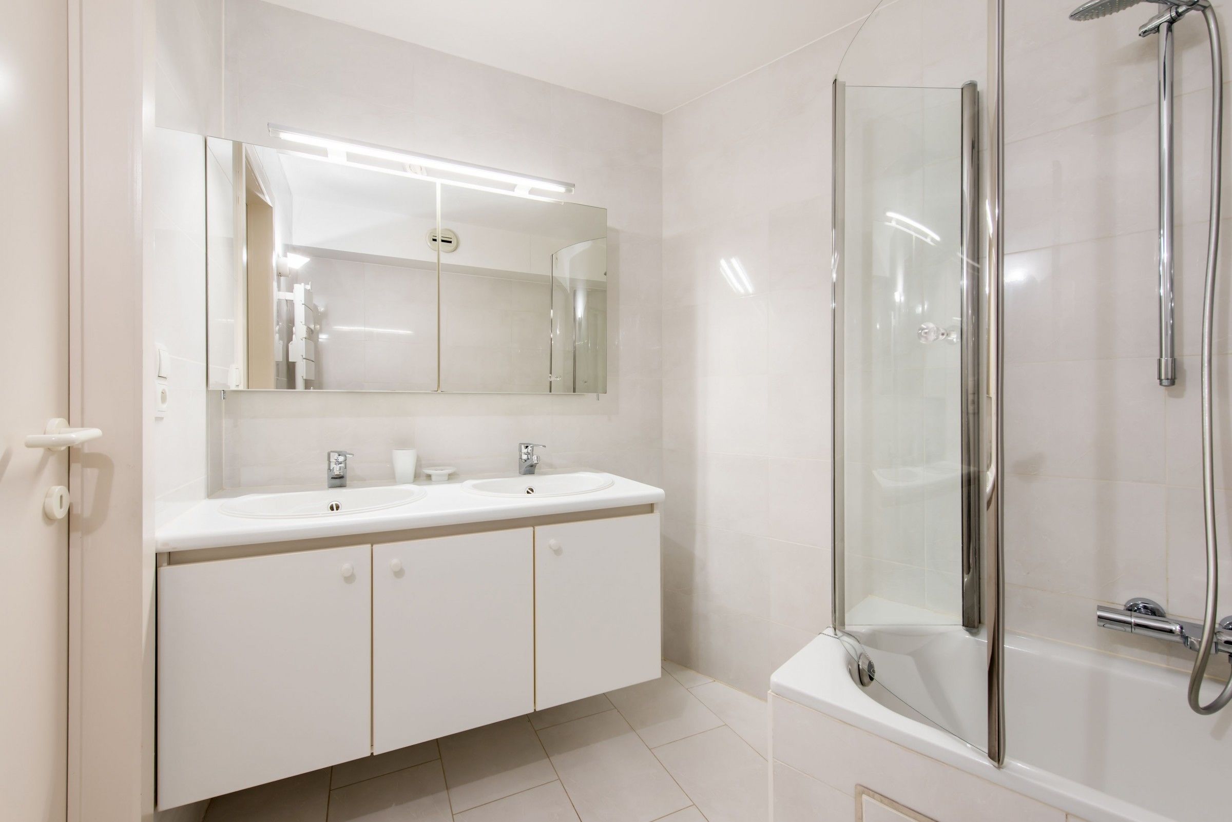 Un baño moderno con ducha de vidrio, un espejo grande y un mueble de tocador doble.