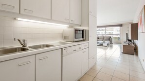 A modern kitchen with white cabinets, a built-in microwave, and a dishwasher. - La Bohème 204 (Koksijde)