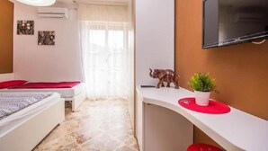 A hotel room with a bed, a desk, a television, and a window with curtains. - B&B Il Muretto (Lascari)