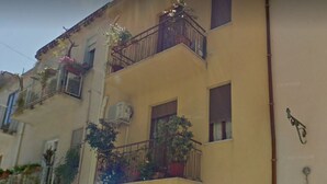 A multi-story building with balconies, potted plants, and a visible storefront. - B&B Il Muretto (Lascari)