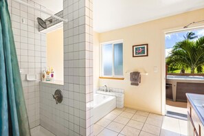 A bathroom with a shower, bathtub, and a window with a view of the outdoors.
