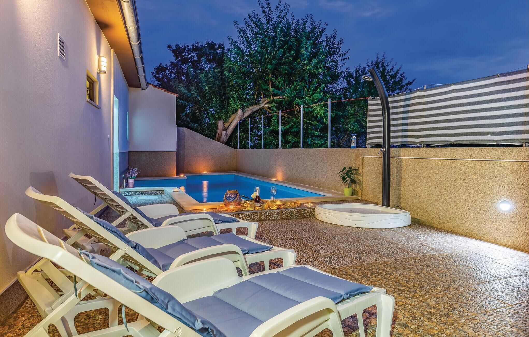 A pool area with lounge chairs, a hot tub, and a tiled floor.