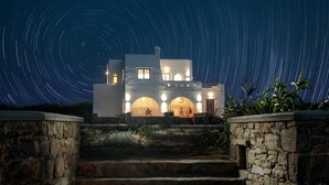 Una casa moderna con una escalera de piedra que conduce a la entrada, bajo un cielo estrellado.