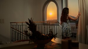 Una mujer de pie junto a un balcón con vistas a la puesta de sol.