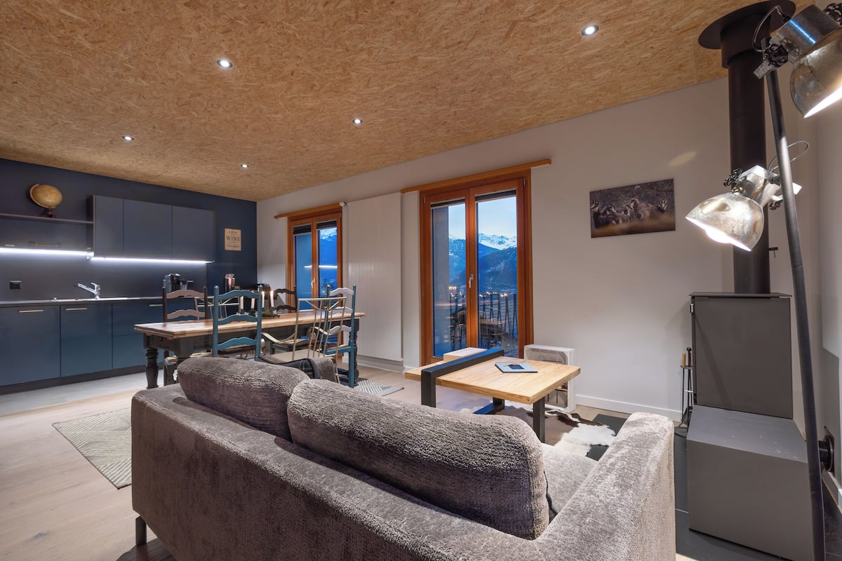 Sala de estar moderna com sofá, área de jantar e cozinha.