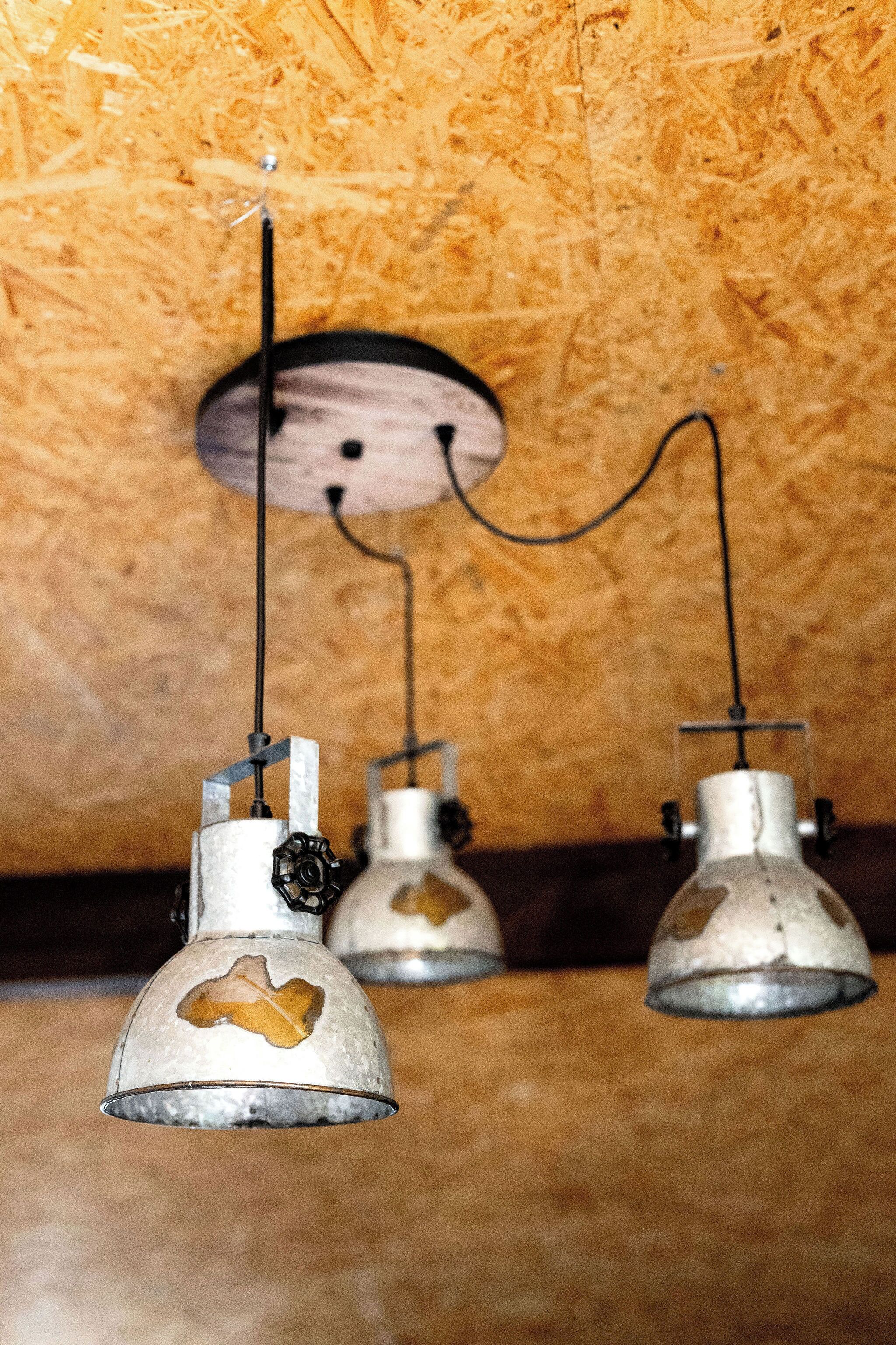 Trois suspensions d’époque, de style vintage, sont suspendues au plafond, dont les câbles sont apparents.
