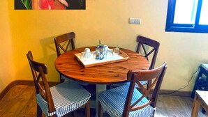 A round wooden dining table with four chairs, a tray with glasses and a pitcher, and a painting on the wall. - Sol Carlos V Apartaments & Suites (Madrid)