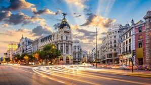 A city street with historic buildings, a prominent ornate building with a golden dome, and a statue on top. - Sol Carlos V Apartaments & Suites (Madrid)