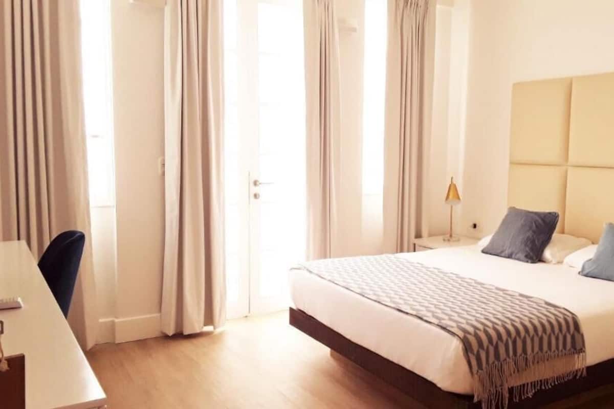 Ein Hotelzimmer mit einem großen Bett, einem Nachttisch mit Lampe und einem Sessel.