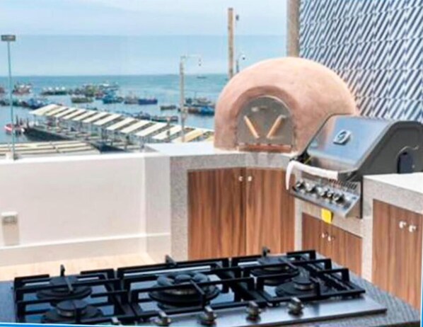 A rooftop with a gas stove, a wood-fired oven, and a view of a marina with boats. - Casa Paracas (Paracas)