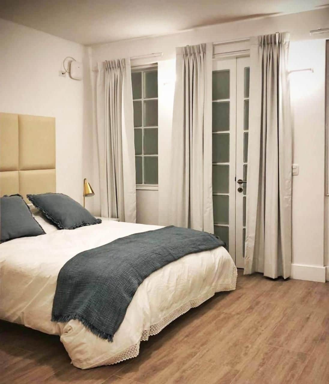 A bedroom with a bed, curtains, a window, and a door.