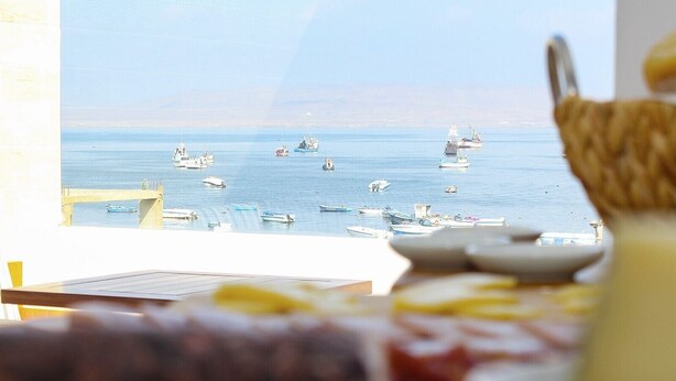 Vista desde una habitación con una mesa lista para el desayuno, con vista a un puerto deportivo y sus barcos.