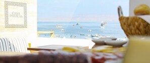 A view from a room with a table set for breakfast, overlooking a marina with boats. - Casa Paracas (Paracas)