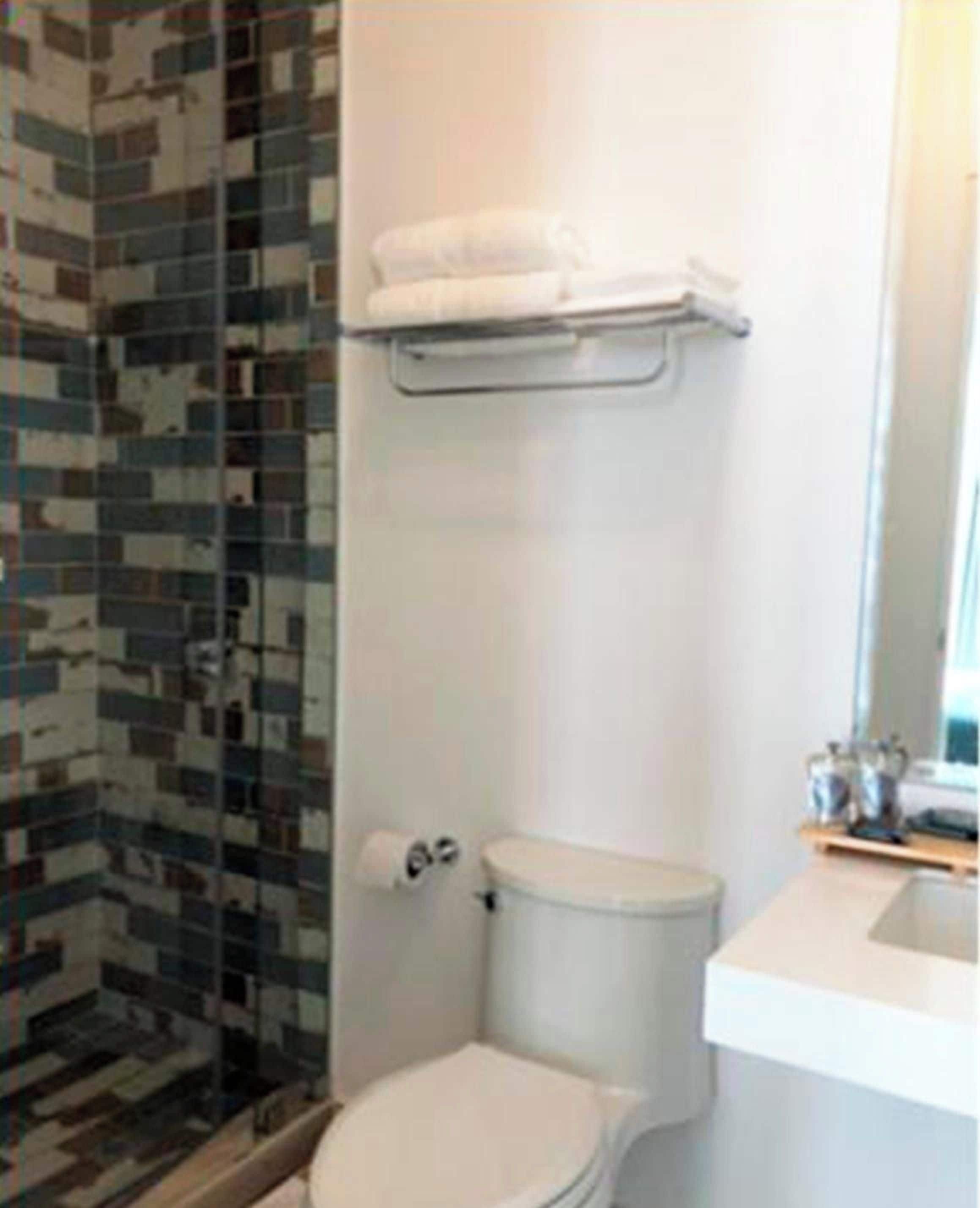 A bathroom with a toilet, a sink, and a shower area with a tiled wall.