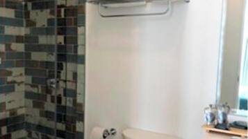 Un baño con inodoro, lavabo y zona de ducha con pared de azulejos.
